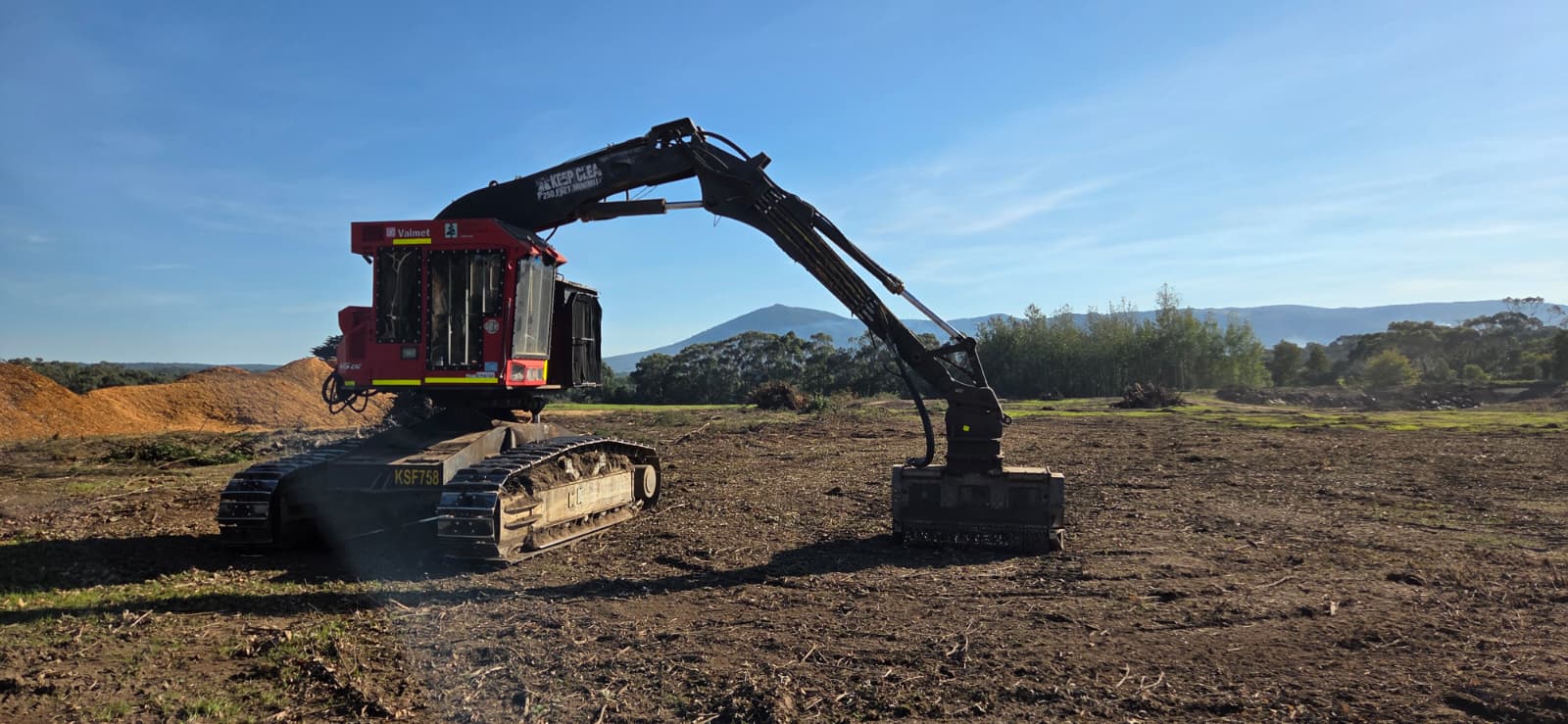Red tracked mulcher clearing vegetation for a residential development