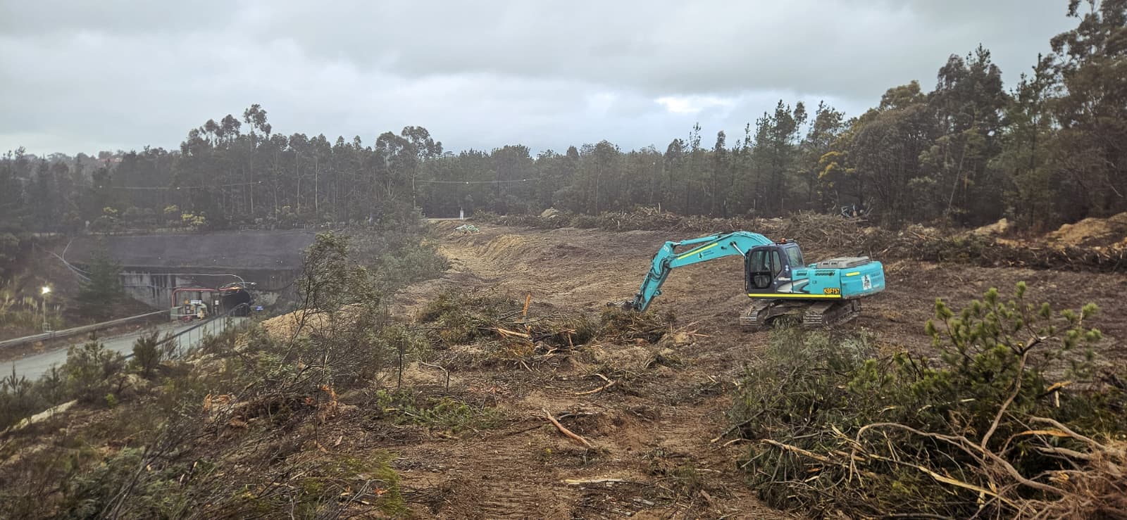 Excavator clearing a vegetation corridor above the mine access road