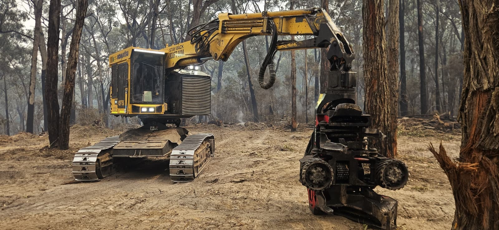 Komatsu harvester working a firebreak through smoky bushland